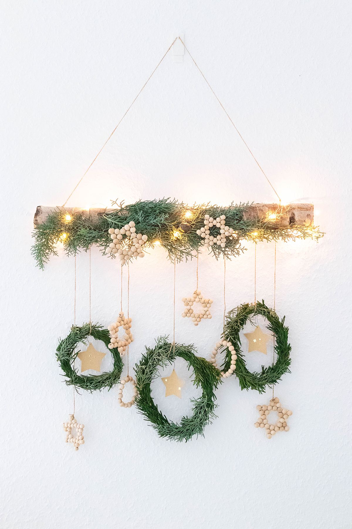 DIY Weihnachtliche Wanddeko mit Holzperlen und Tannengrün